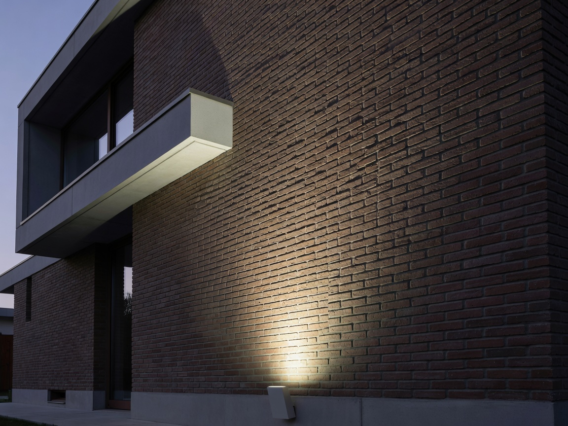 Architectural exterior facade grazing luminaire revealing tactile brick texture on modern Belgian villa