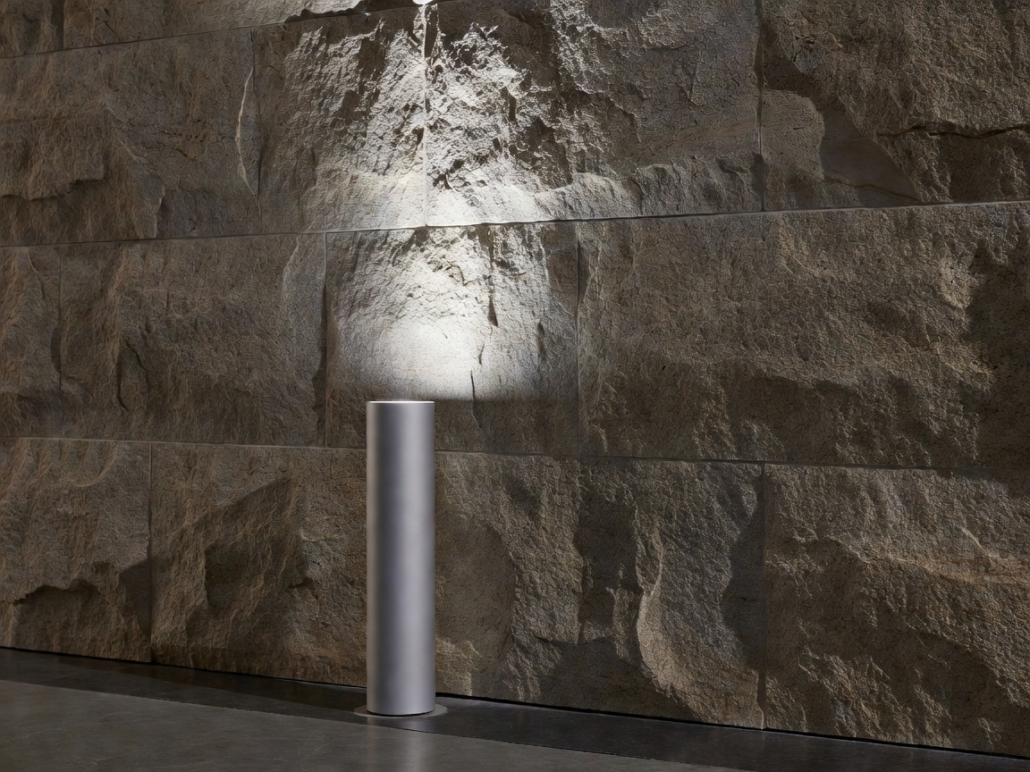 Minimalist architectural bollard and grazing luminaire highlighting textured stone facade